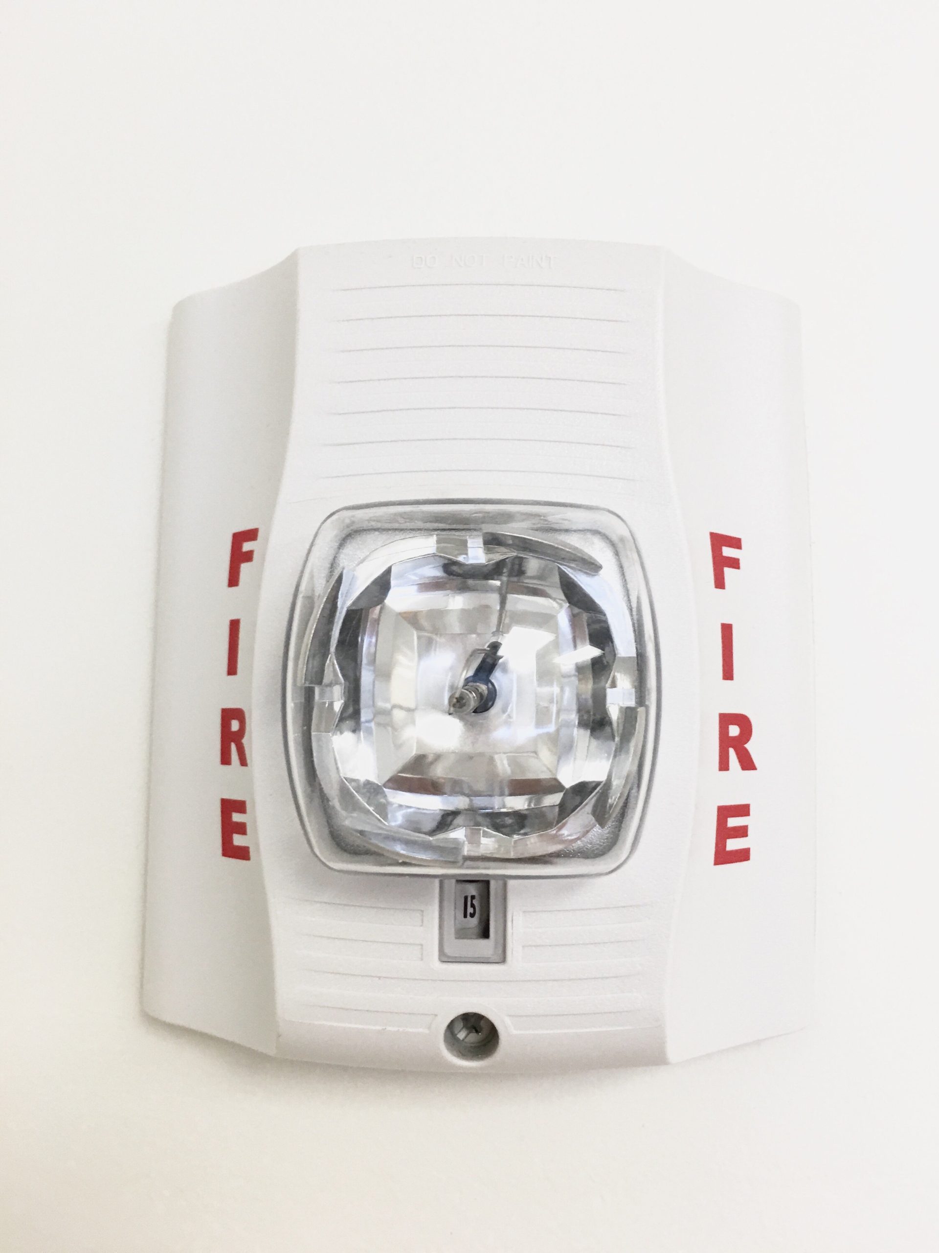 White wall-mounted fire alarm strobe light.